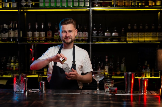 Mężczyzna barman robi koktajl z shakerem