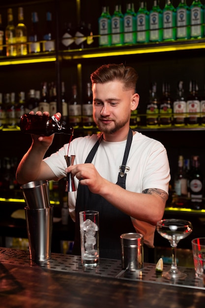 Bezpłatne zdjęcie mężczyzna barman robi koktajl z shakerem