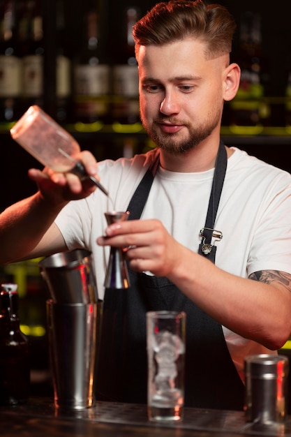 Bezpłatne zdjęcie mężczyzna barman robi koktajl z shakerem