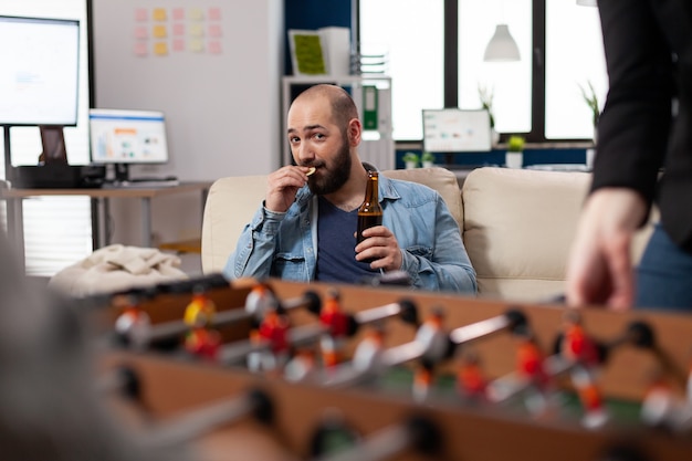Bezpłatne zdjęcie mężczyzna bawi się pijąc piwo po pracy w biurze