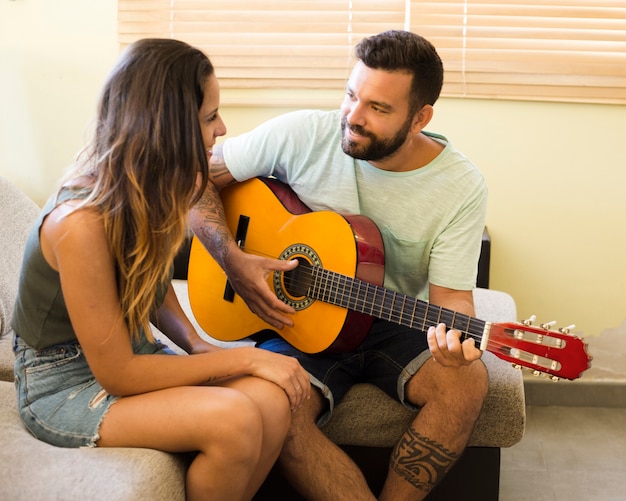 Mężczyzna bawić się gitarę dla jego pięknej żony w domu