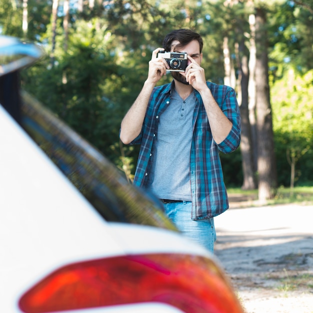 Bezpłatne zdjęcie mężczyzna bierze fotografię obok samochodu