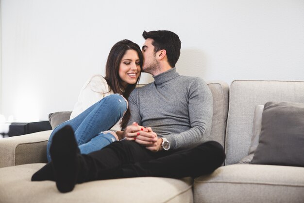 Mężczyzna całuje swojego partnera na kanapie