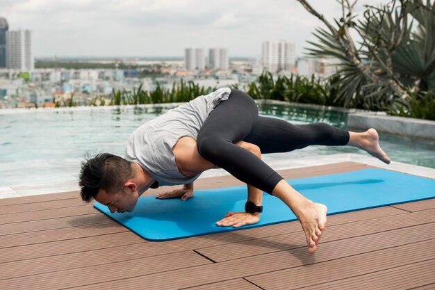 Mężczyzna ćwiczy jogę na świeżym powietrzu przy basenie