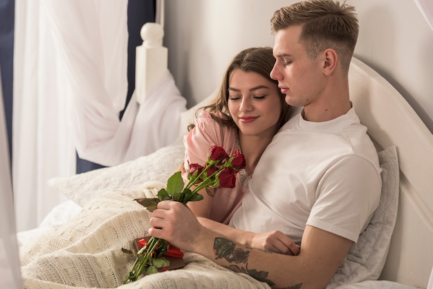 Mężczyzna daje czerwone róże kobieta w łóżku