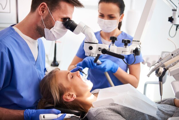 Mężczyzna dentysta pracujący z mikroskopem stomatologicznym