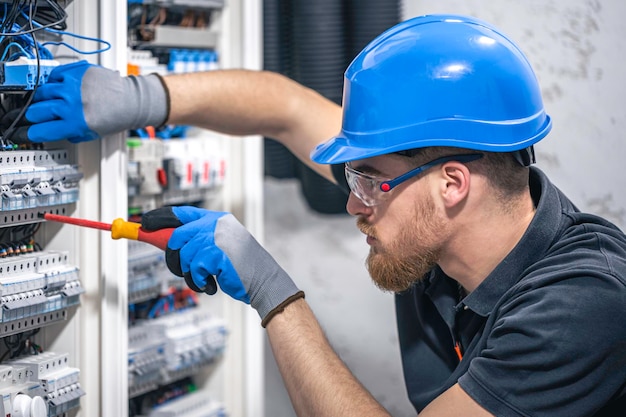 Mężczyzna elektryk pracuje w rozdzielnicy z elektrycznym kablem łączącym