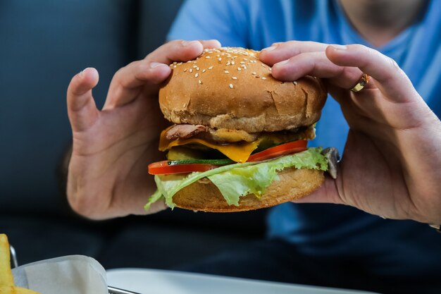 Mężczyzna gospodarstwa burger wołowy sałata ser pomidor ogórek jajko widok z boku