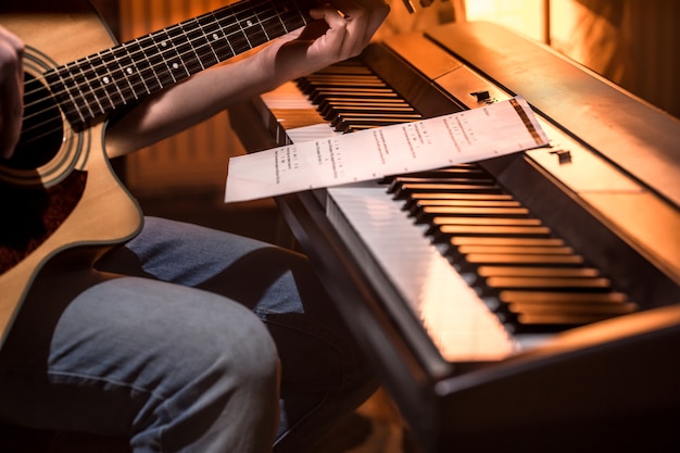 mężczyzna gra na gitarze akustycznej i fortepianie z bliska