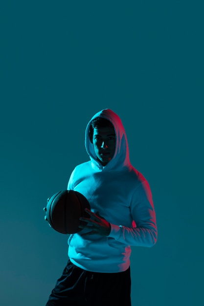 Bezpłatne zdjęcie mężczyzna gra w koszykówkę sam na sam z fajnymi światłami