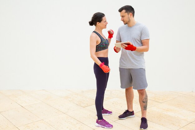 Mężczyzna i kobieta omawia plan treningowy z owiniętymi rękami