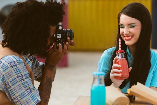 Mężczyzna i kobieta pozują razem w stylu retro z aparatem i napojem