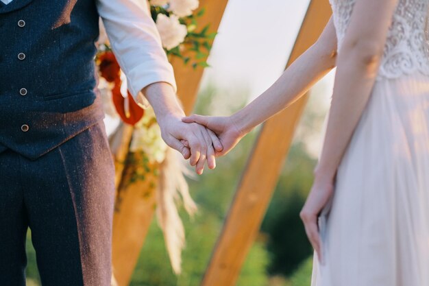 Mężczyzna i kobieta trzymają się razem podczas ceremonii ślubnej na świeżym powietrzu