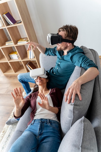 Mężczyzna i kobieta w domu na kanapie przy użyciu zestawu słuchawkowego wirtualnej rzeczywistości