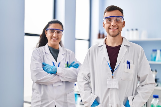 Bezpłatne zdjęcie mężczyzna i kobieta w mundurze naukowca, stojący z rękami skrzyżowanymi w laboratorium