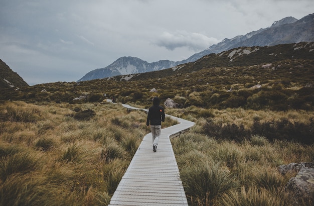 Mężczyzna idący w Hooker Valley z widokiem na Mount Cook w Nowej Zelandii