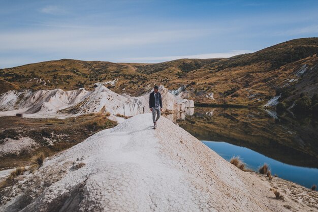 Mężczyzna idący w pobliżu Blue Lake Walk w Nowej Zelandii otoczony górami