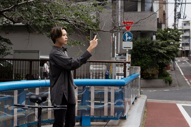 Mężczyzna jadący na rowerze po mieście i robiący selfie ze smartfonem
