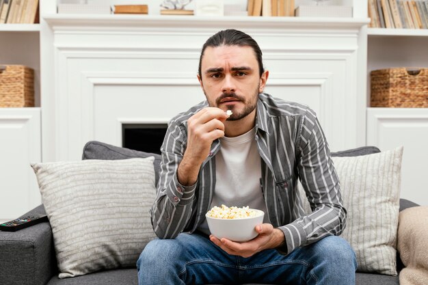 Mężczyzna je popcorn i ogląda telewizję