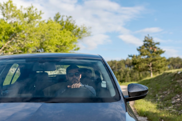 Bezpłatne zdjęcie mężczyzna jedzie samochód z okularami przeciwsłonecznymi