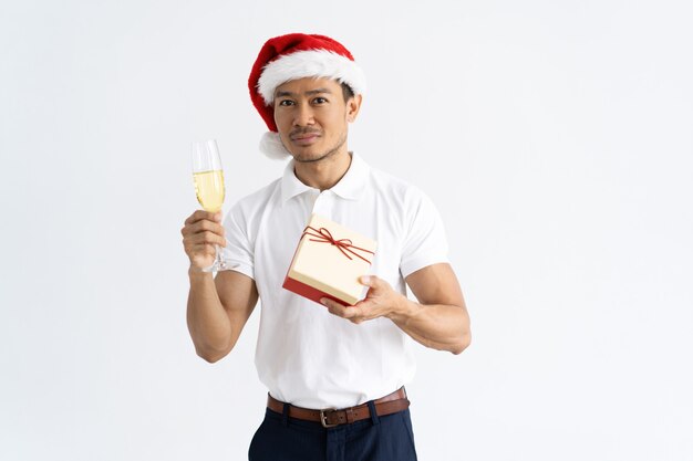 Mężczyzna jest ubranym Santa kapelusz, trzymający prezenta pudełko i czara