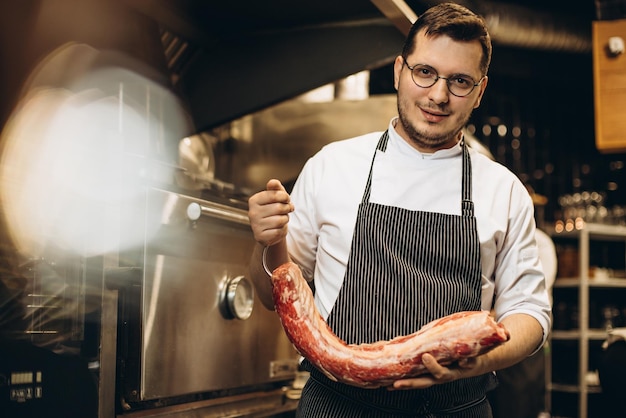 Bezpłatne zdjęcie mężczyzna kucharz trzyma dużą część mięsa w kuchni restauracji