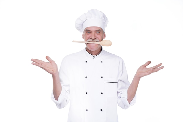Mężczyzna kucharz w mundurze trzymający drewnianą łyżkę na myszy, pozostając na białej ścianie
