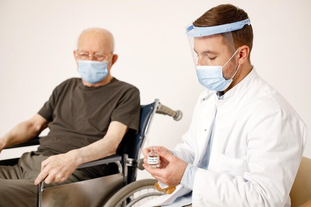 Bezpłatne zdjęcie mężczyzna lekarz i staruszek na wózku inwalidzkim na białym tle