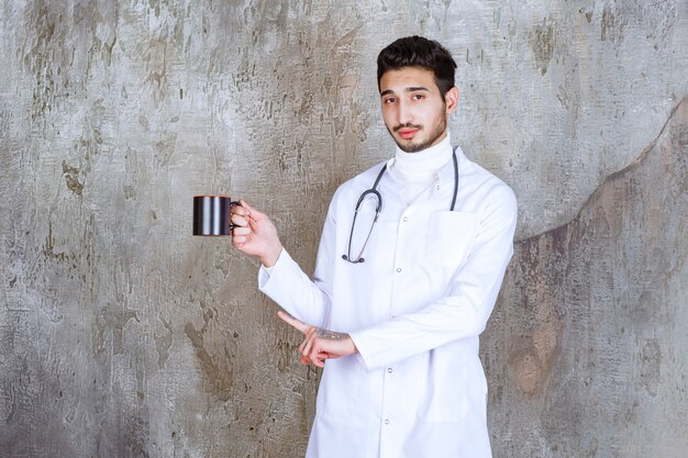 Mężczyzna lekarz trzyma filiżankę kawy ze stetoskopem.