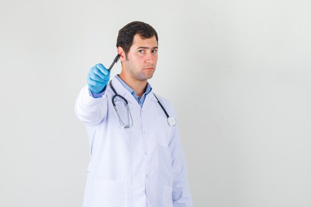 Mężczyzna lekarz wskazując piórem do przodu w białym fartuchu, widok z przodu rękawiczki.
