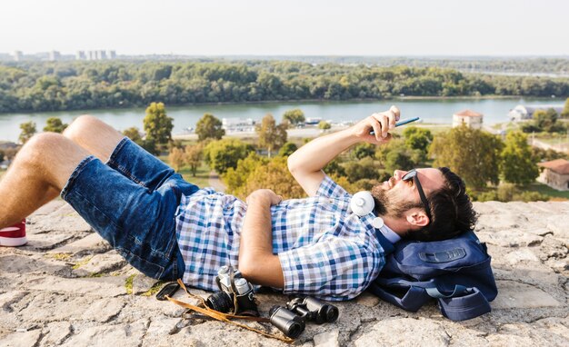 Mężczyzna lying on the beach na zmielonym używa telefonie komórkowym