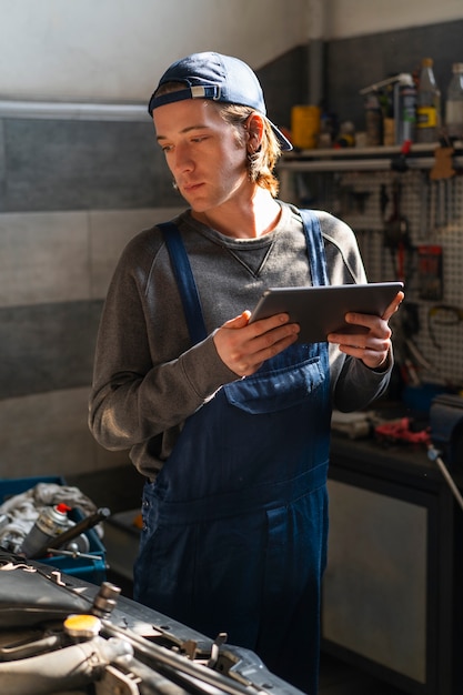 Mężczyzna mechanik samochodowy za pomocą tabletu w warsztacie samochodowym