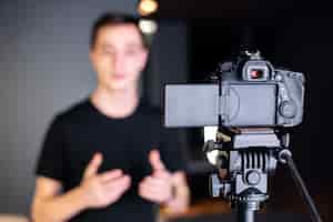 Bezpłatne zdjęcie mężczyzna mówiący do kamery, nagrywający siebie na vloga. praca z domu. młody twórca treści
