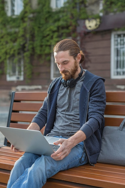 Mężczyzna na ławce pracuje na laptopie