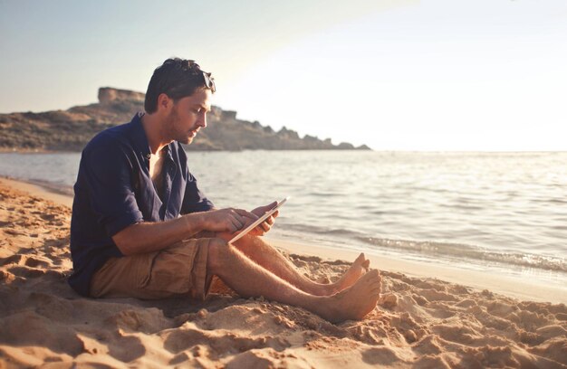 mężczyzna na plaży z tabletem