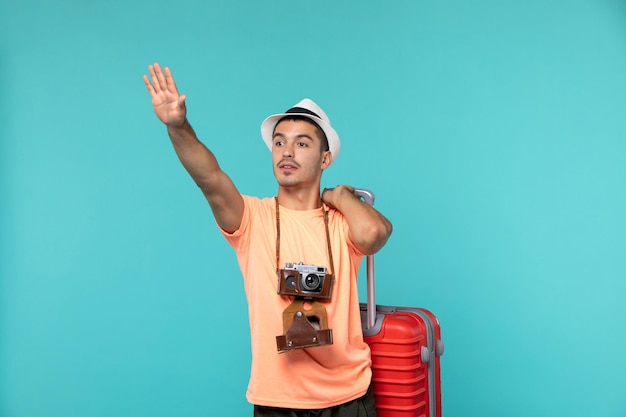 mężczyzna na wakacjach trzymający dużą czerwoną walizkę na niebiesko