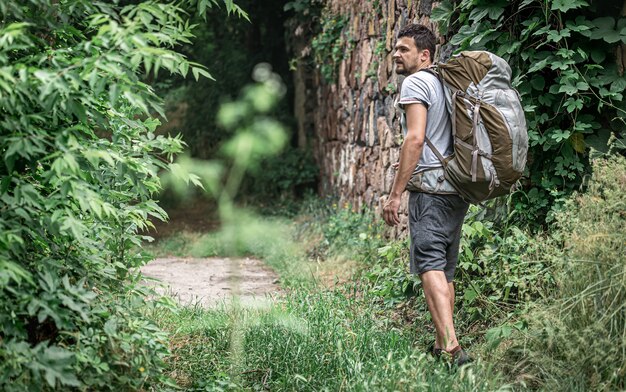Mężczyzna na wędrówce z dużym plecakiem podróżuje po lesie.