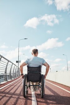 Mężczyzna na wózku inwalidzkim na zewnątrz, widok z tyłu