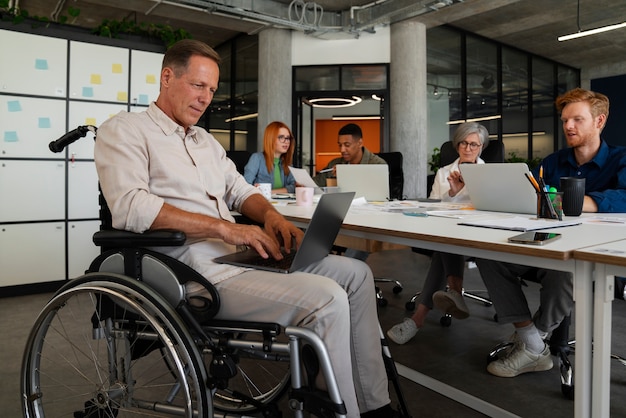 Mężczyzna na wózku inwalidzkim wykonujący włączającą pracę biurową