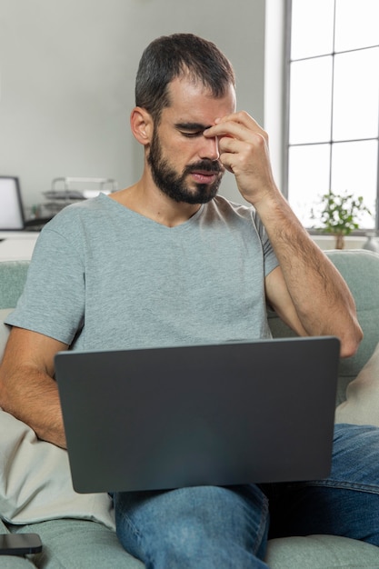 Bezpłatne zdjęcie mężczyzna odczuwa ból oczu podczas pracy na laptopie w domu