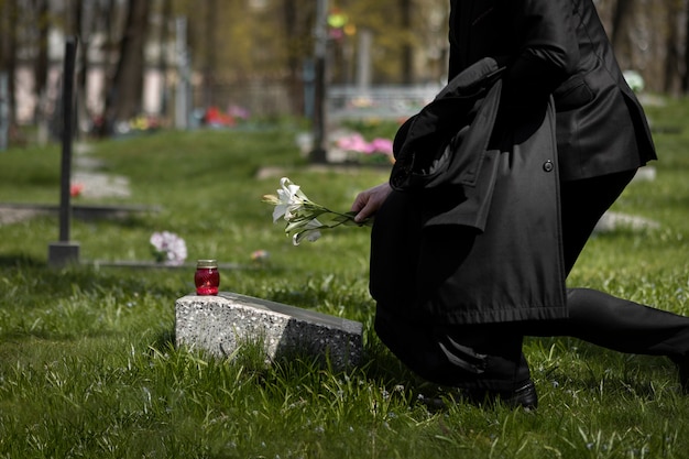 Bezpłatne zdjęcie mężczyzna oddający szacunek nagrobkowi na cmentarzu
