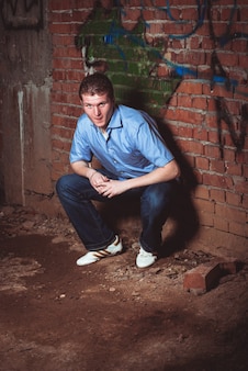 Mężczyzna oparty o ceglaną ścianę w opuszczonym niedokończonym domu