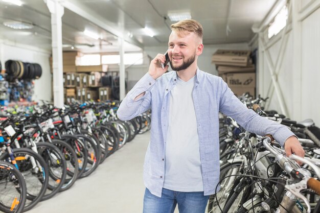 Mężczyzna opowiada na telefonie komórkowym w rowerowym warsztacie