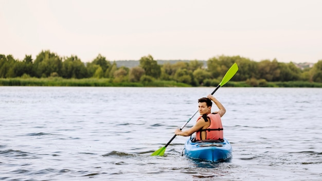 Mężczyzna paddle kayaking nad jeziorem przyglądającym z powrotem