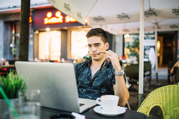Mężczyzna patrzeje laptopu ekran w kawiarni