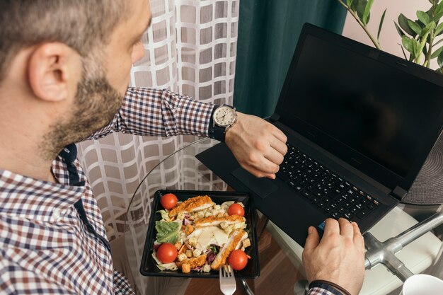 Mężczyzna patrzeje zegarek podczas gdy używać laptop