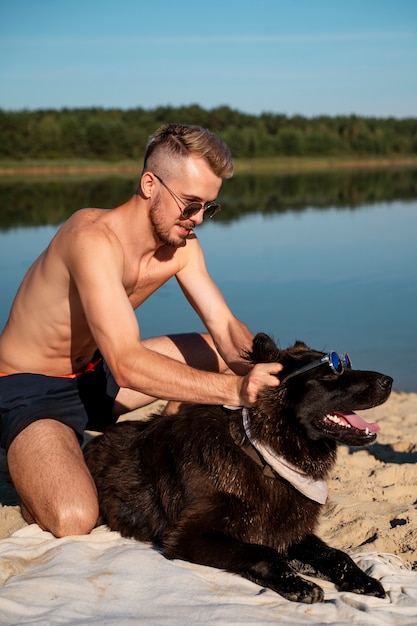 Bezpłatne zdjęcie mężczyzna pieszczący psa w widoku od strony plaży