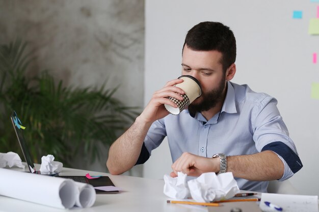 Mężczyzna pije kawę przy biurem