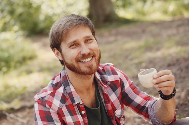 mężczyzna pije kawę w lesie