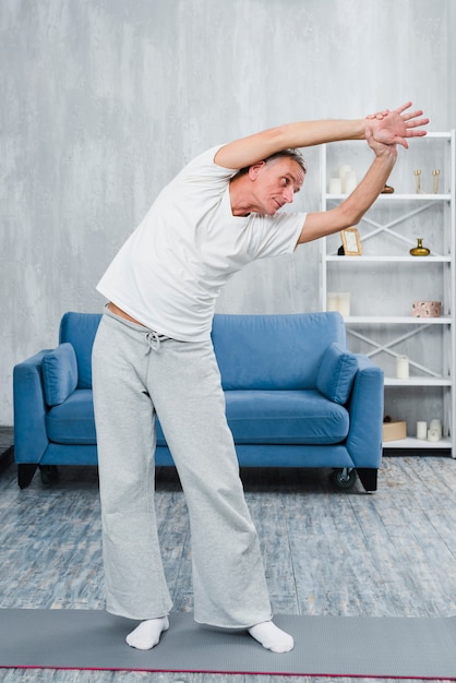 Bezpłatne zdjęcie mężczyzna pochyla się podczas robienia jogi w pokoju
